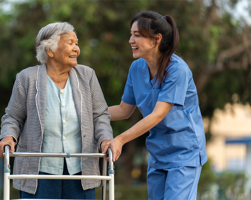 caregiver laughing with older woman using a walker